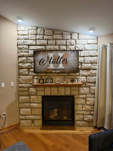 Customer's rustic Family Last Name Sign mounted above the mantel of a stone fireplace.