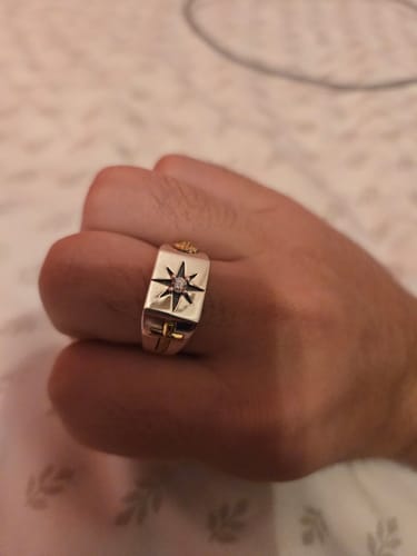 Customer's hand wearing the silver vintage ring, showing the star design and a gold cross on the band.