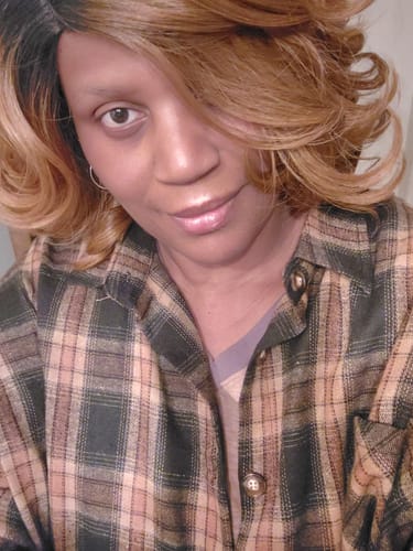 Customer wearing a stylish, shoulder-length ombre wig with dark roots and wavy blonde ends.