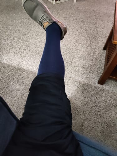 Customer wearing the dark blue Performance Eucalyptus Compression Socks while seated, with their leg propped up.