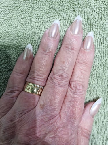 Customer's hand showing the Sugar Coat press-on nails, which are almond-shaped with a pearlescent French manicure finish.