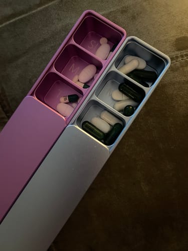 Customer's Weekly AM-PM Vitamin Case 2.0, shown open with pills inside the purple and silver metal sections.