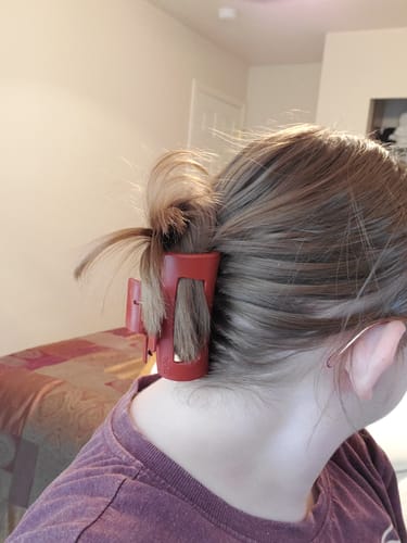 Close-up of a reviewer's hair held up in a messy bun by a red cloud clip at the nape of their neck.