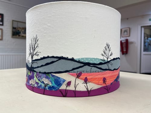 Customer's lampshade with an intricate, embroidered landscape made using the darning foot.