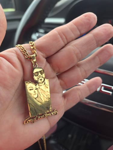 Customer holding a gold-colored photo engraved pendant necklace in their palm, showing an image of two people and 'LongLiveTimothy'.