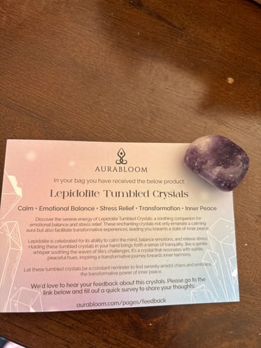 Customer's purple Lepidolite tumbled crystal from the VIP Crystal Club, shown with its descriptive card on a table.