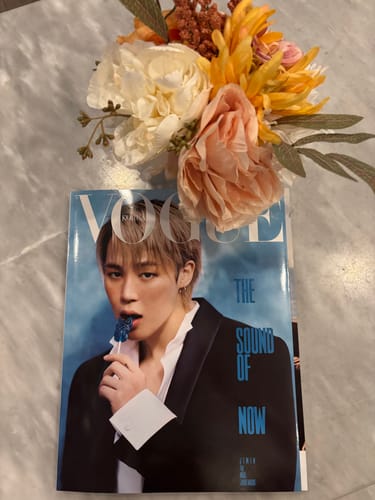 Customer's copy of the VOGUE magazine featuring BTS's Jimin, displayed on a marble surface with a floral bouquet.