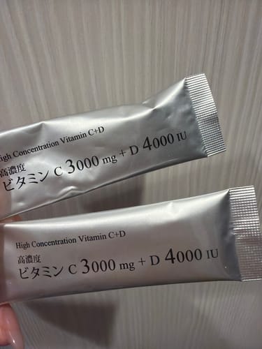 レビュアーが手に持つ、「ビタミンC+D」の銀色の個包装2袋。