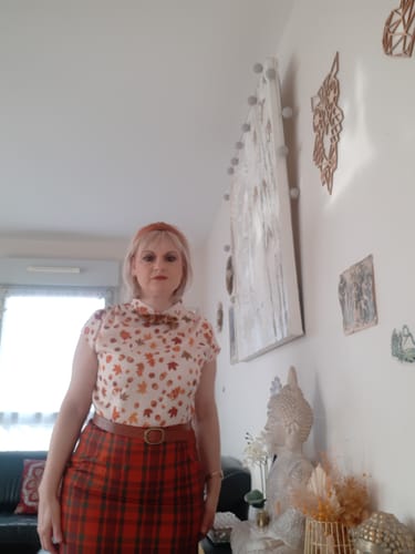 Une cliente pose dans son salon, portant une tenue qui n'est pas le produit.