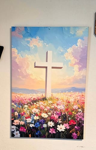 Customer's Cross Floral Field Faith Wall Art hanging on a wall, depicting a white cross in a colorful field of flowers.