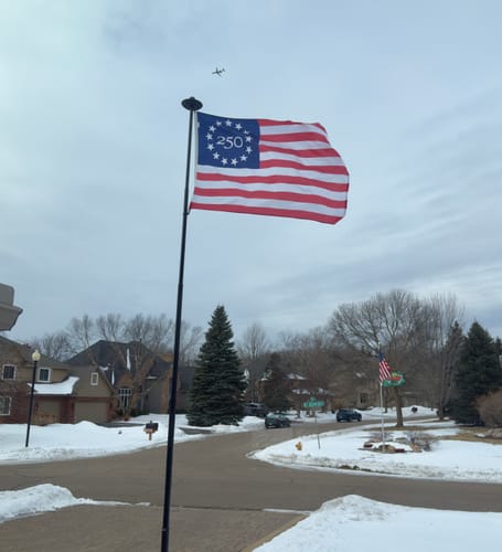 Reviewer's America 250™ Betsy Ross Flag waving on a flagpole in a snowy neighborhood.