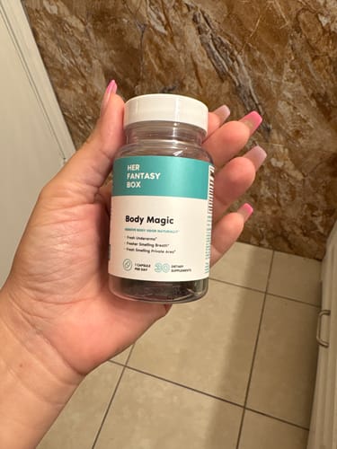 Customer holding a clear bottle of Her Fantasy Box Body Magic supplements in their hand.