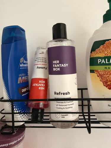 Reviewer's Refresh Plant Based Yoni Gel Wash in a black shower caddy with other toiletries.