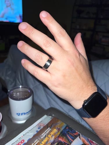 Customer wearing the hammered tungsten The Atlas ring on their finger in a casual indoor setting.