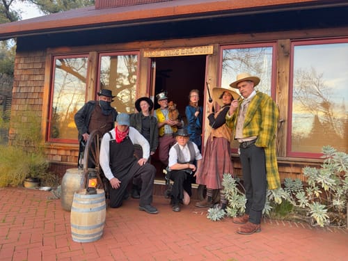 Reviewer and guests in cowboy costumes posing outside a building for the Wild West murder mystery game.