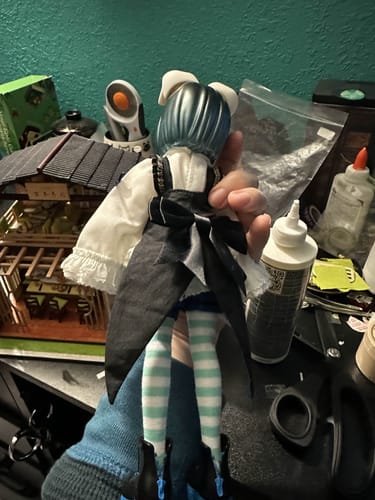Reviewer holding the UF Doll Blueberry Yogurt BJD, showing the back of its outfit and striped leggings.