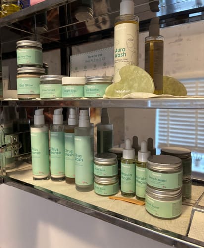 Customer's collection of Wild Mint skincare, including the 5-Step Clear Skin Kit, neatly arranged on mirrored shelves.