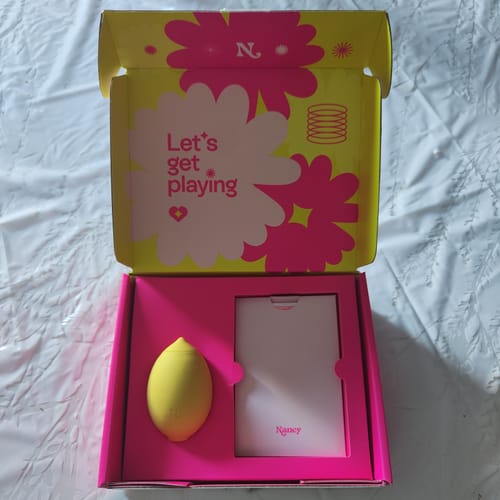 Customer's yellow Lem Clitoral Massager in its vibrant pink and lime green open box.