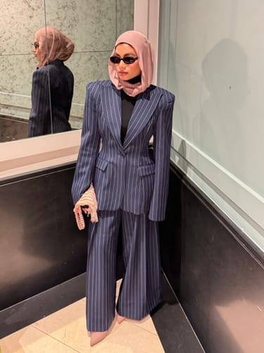 Reviewer looking stylish in the Pinstripe Suited Blazer with power shoulders and matching wide-leg pants.