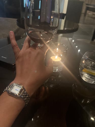 Customer's silver-toned Vienna Watch on their wrist, seen at a candlelit table.
