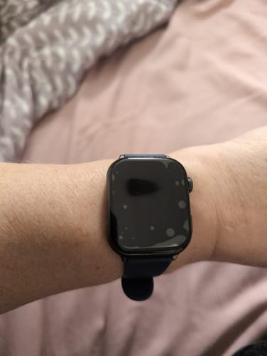 Close-up of a reviewer's wrist wearing a black smartwatch with a dark screen.