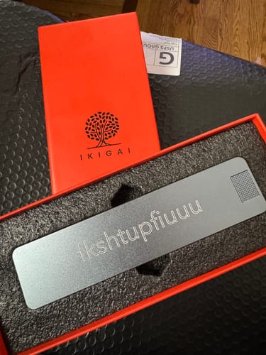 Customer's custom-engraved metal pill case resting inside its open red box.