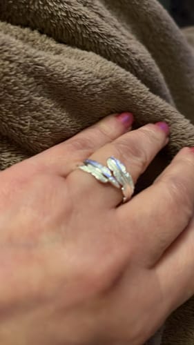 A customer's hand with pink nail polish wearing the silver Feather From An Angel Ring.