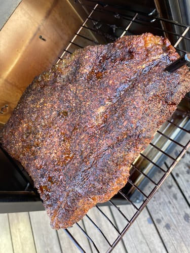Customer's seasoned Halal Beef Brisket cooking on a smoker rack