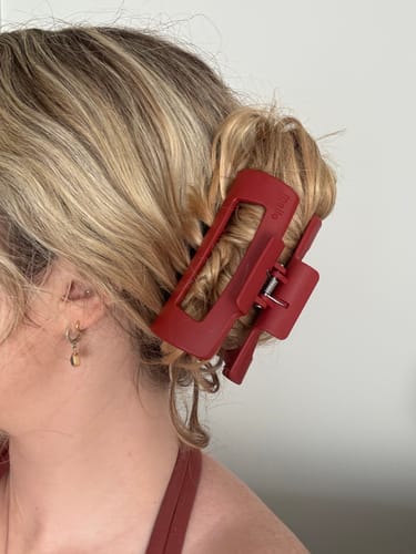 Reviewer's red cloud clip securely holding their blonde hair in a bun.
