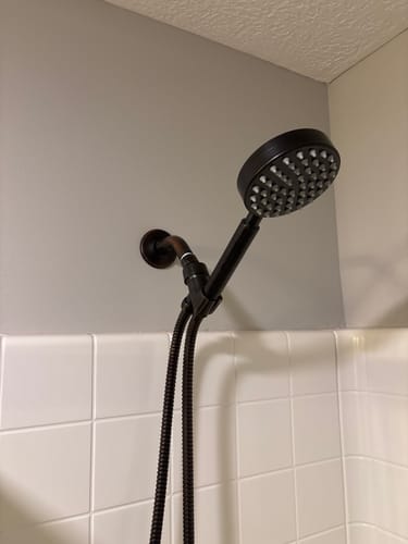 Customer's dark 1-Spray Handheld Shower Head Set installed in a white tiled shower.