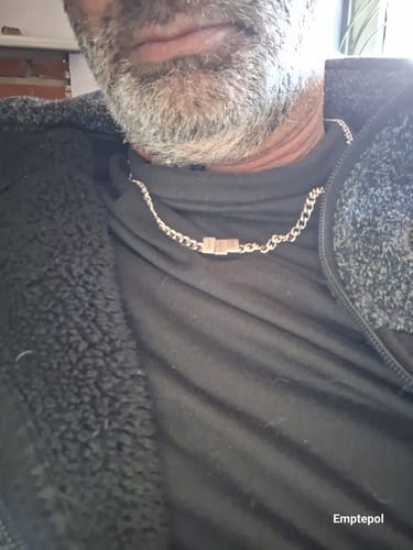 A close-up of a reviewer wearing the stainless steel Legacy necklace over a black t-shirt.