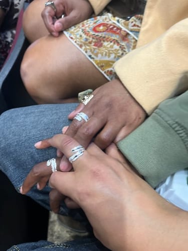 Close-up of several people holding hands, each wearing the matching Feather From An Angel Ring.