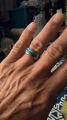 A close-up of a customer's hand wearing the silver Vanguard ring with a bright blue inlay.