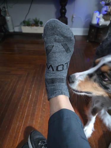 Customer wearing a grey Men's Alpaca Sock on their foot, showing the textured details and ankle-length fit.