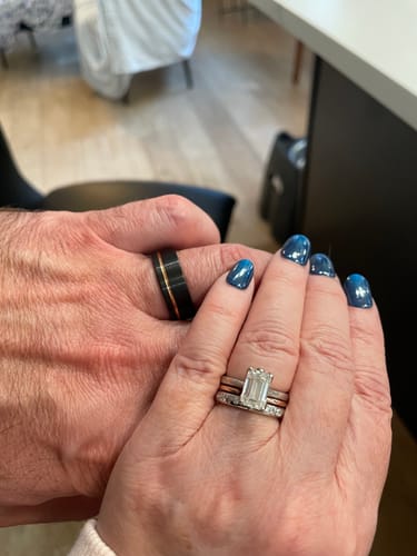 Customer wearing the black Loki ring with a gold inlay, holding hands with another person.