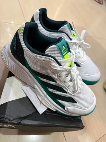 Customer's white and green adidas Courtquick Padel Shoes resting on top of the product box.