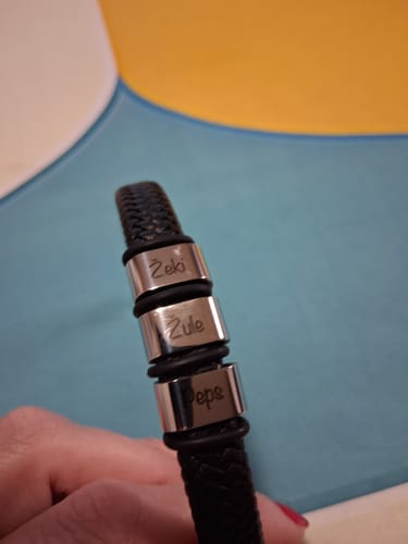 Customer's close-up of the black braided Viking Bracelet with three silver beads engraved with names.