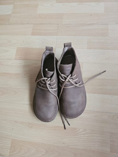 Reviewer's brown vintage ankle boots with round toes, shown on a light wood floor.