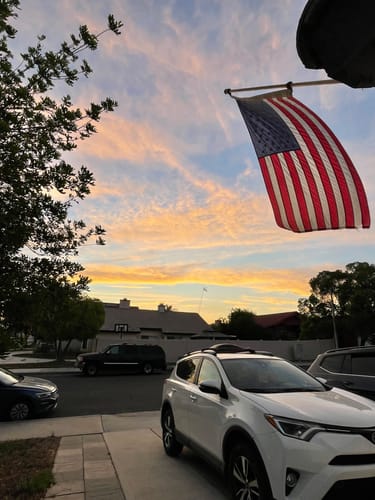 Customer's heavy duty American flag flying from a house at sunset.