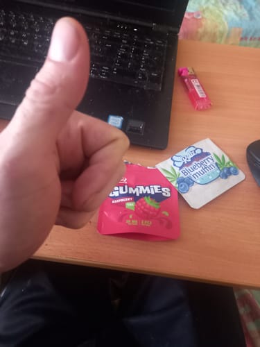 Customer gives a thumbs-up over a red packet of raspberry ROLLZ THC gummies on a desk.