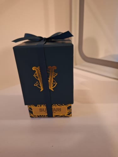 Customer's Surfari perfume box, showing the dark blue packaging with a matching ribbon tied around it.