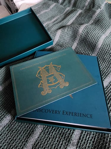 Customer's dark teal Discovery Set box, with its lid and an included booklet resting on a blanket.