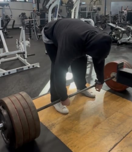 Reviewer in a gym preparing to lift a heavy barbell using the Versa Gripps XTREME for grip support.
