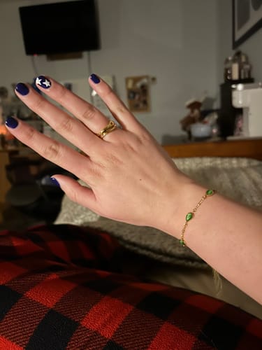 Customer's hand with a dark blue manicure wearing the gold Madison Wave Ring on their finger.