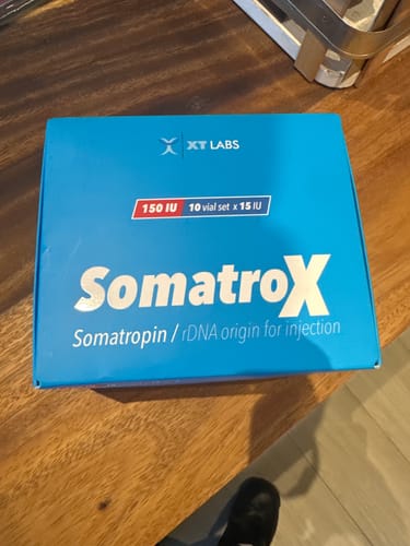 Un cliente muestra la caja azul de Somatrox 150 UI sobre una mesa.