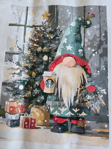Customer's completed Surprise Painting canvas, showing a Christmas gnome holding a coffee cup next to a tree and presents.