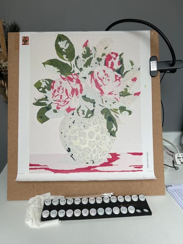 Customer's Wild Roses paint by number kit in progress, showing the partially painted canvas with paint pots and brushes below.