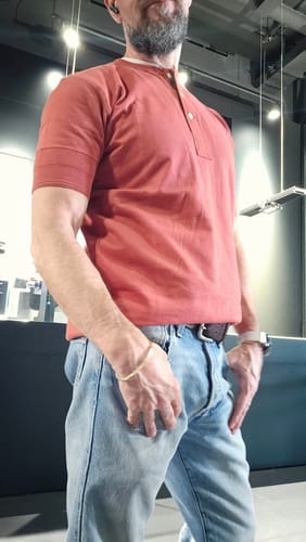 Customer wearing the reddish-brown Henley T-shirt, showing the product's slim fit.