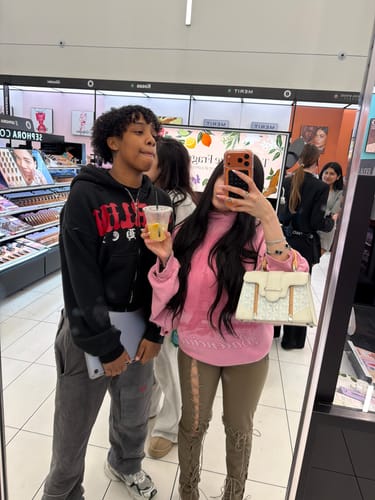 Reviewer taking a mirror selfie with a friend, wearing the lace-up Snake Heels.