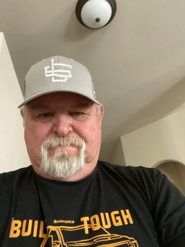 A reviewer wearing the light grey Subzero Trucker Cap with its white logo.